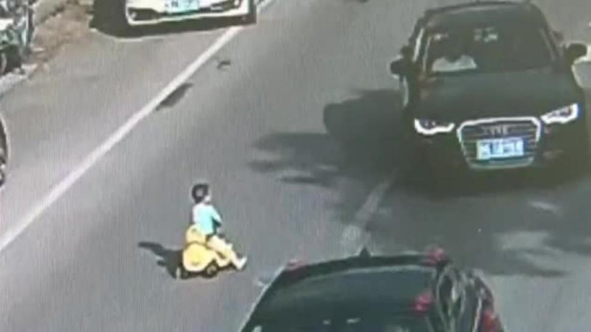 Un niño chino se mete con su coche de juguete en una autopista en hora punta.