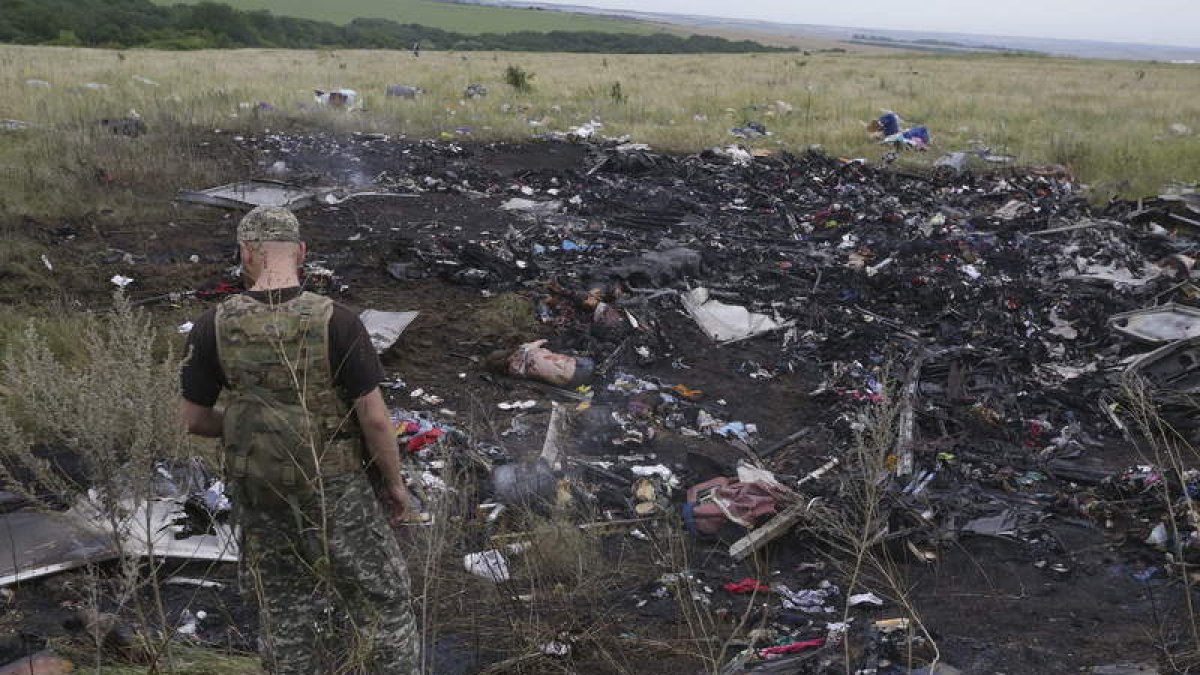 Un rebelde prorruso observa varios cadáveres junto a los restos del Boeing 777.