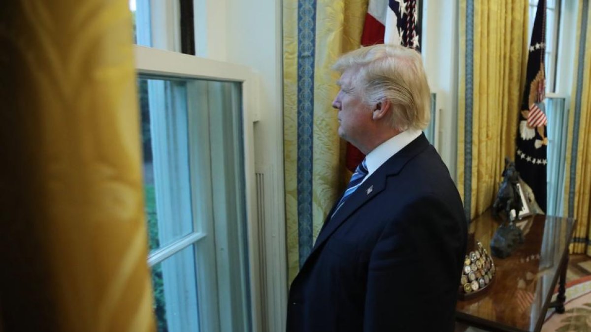 Trump mira por una ventana del Despacho Oval durante la entrevista con motivo de sus 100 días en la Casa Blanca.