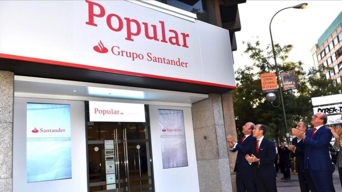 Directivos del Santander ante una de las primeras oficinas del Popular que ya ha adoptado la imagen corporativa del grupo cántabro, en Madrid