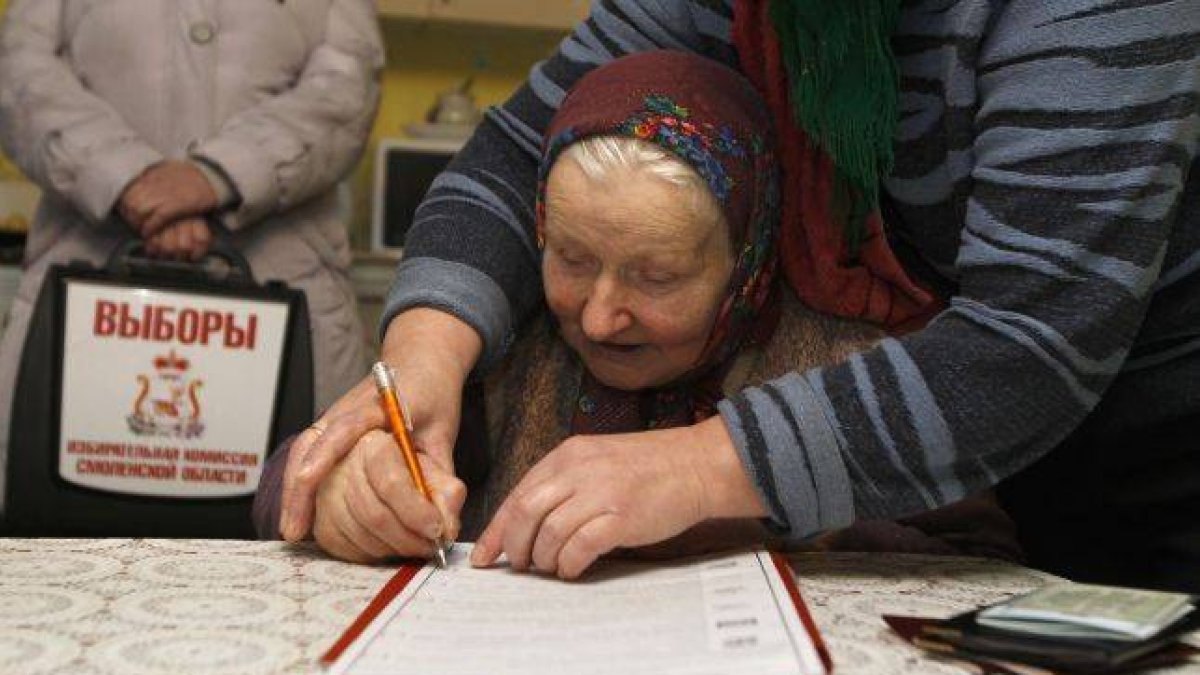 Una anciana es ayudada por su hija a rellenar una papeleta en Oster.