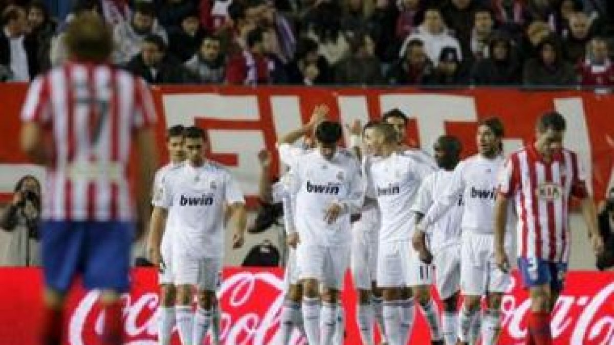 Los jugadores del Madrid celebran la victoria ante la desazón de los atléticos.