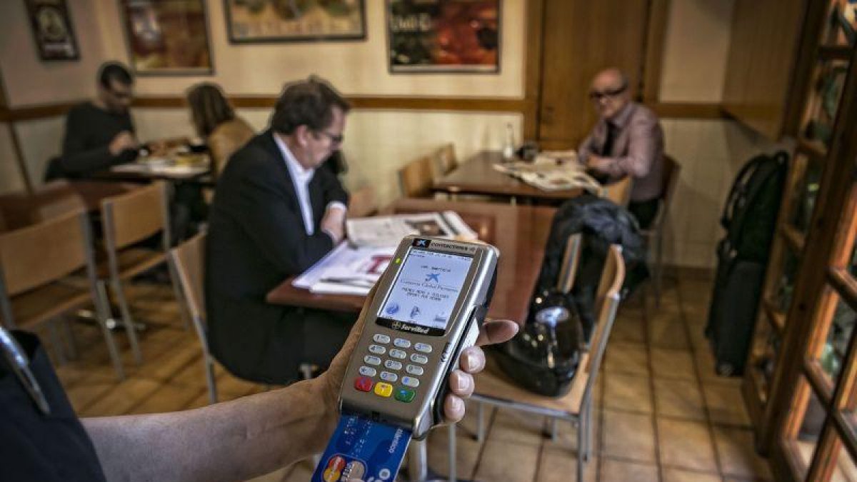 Un camarero cobra con un datáfono a un cliente de un bar de Barcelona.