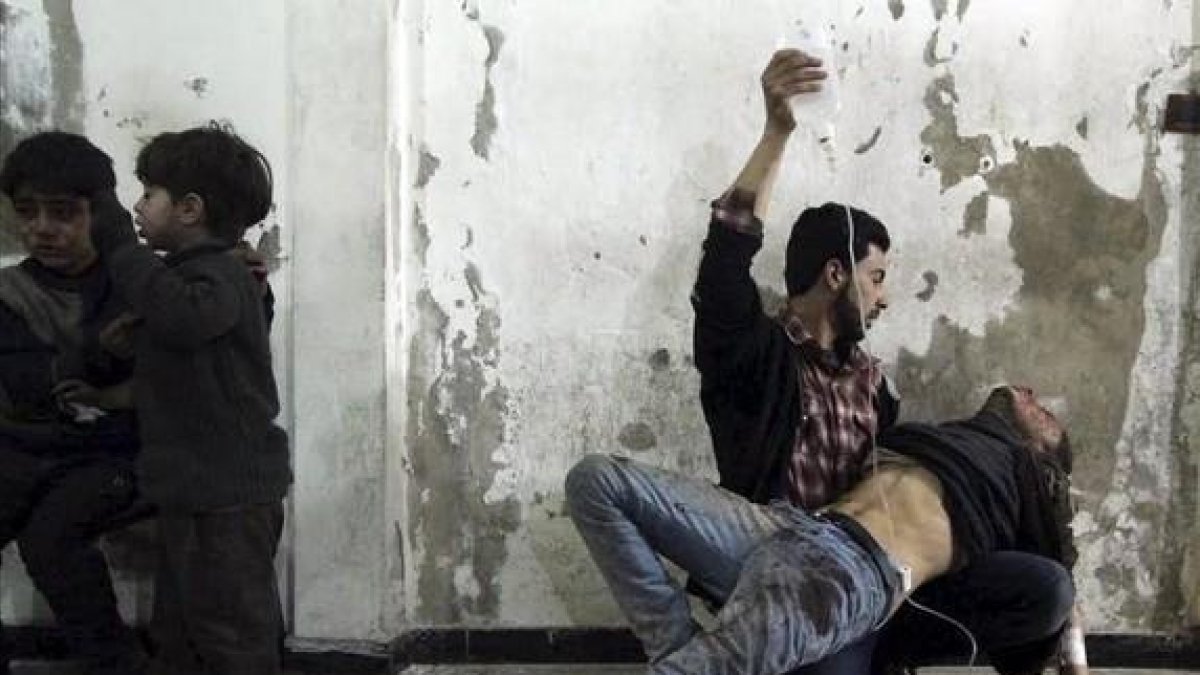 Un hombre da asistencia médica a un herido tras un ataque de las fuerzas del régimen al barrio de Duma, en Damasco.