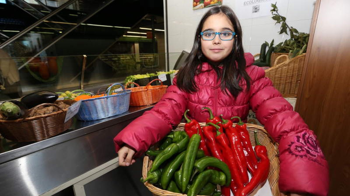 Esther Núñez, con una cesta de pimientos del Bierzo, ayer en la frutería del Mercado de Abastos de Ponferrada.