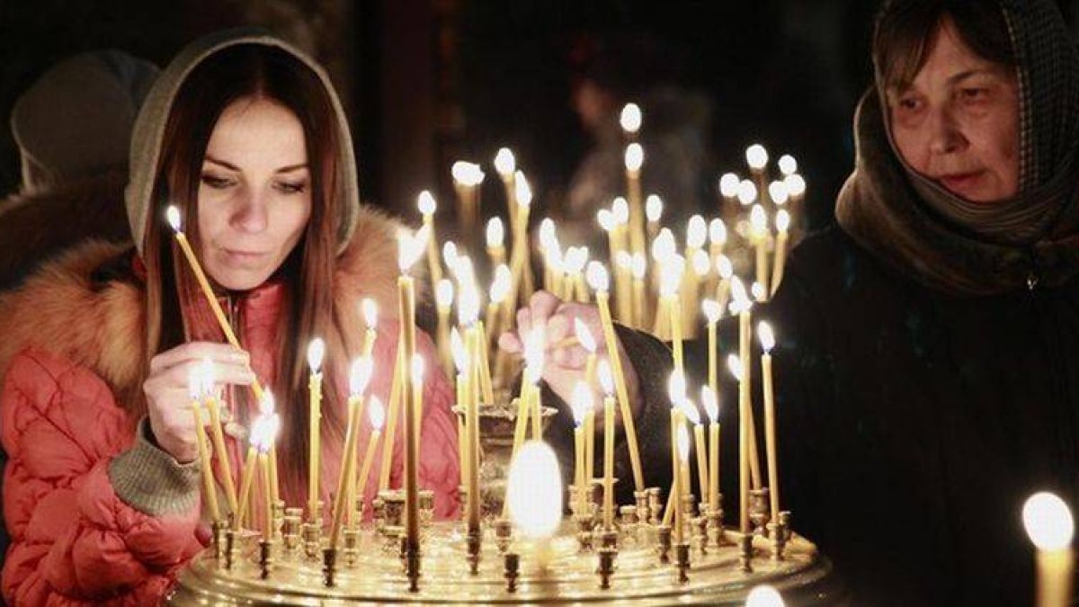 Dos mujeres encienden velas durante una misa en una iglesia de Kiev, este domingo.