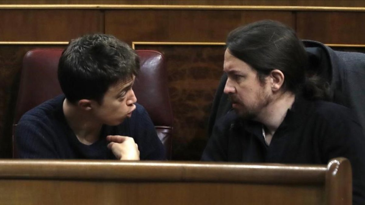Los máximos dirigentes de Podemos, Iñigo Errejón y Pablo Iglesias, discuten en sus escaños del Congreso.