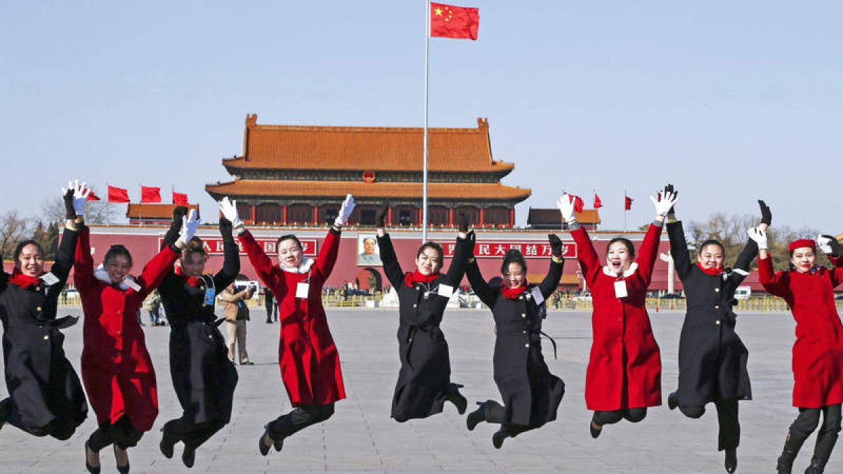 Un grupo de administrativas salta para una foto de recuerdo en la plaza de Tiananmen.