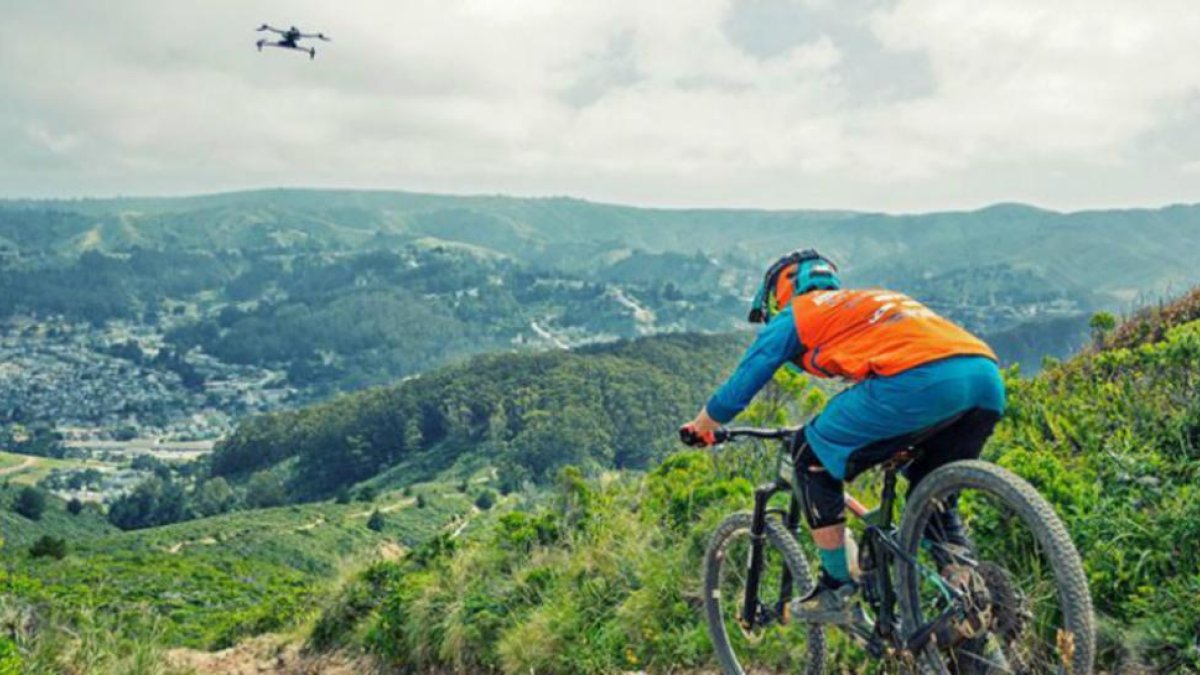 Un ciclista de montaña seguido de cerca por su dron autónomo Airdog.