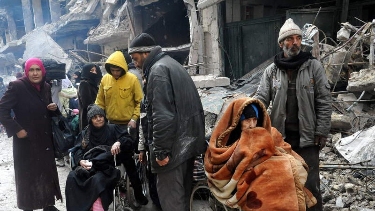 Varios sirios son evacuados de un campamento palestino en Damasco.