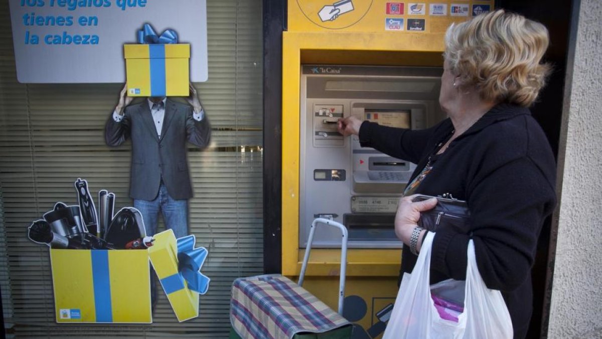 Una amujer saca dinero de un cajero.