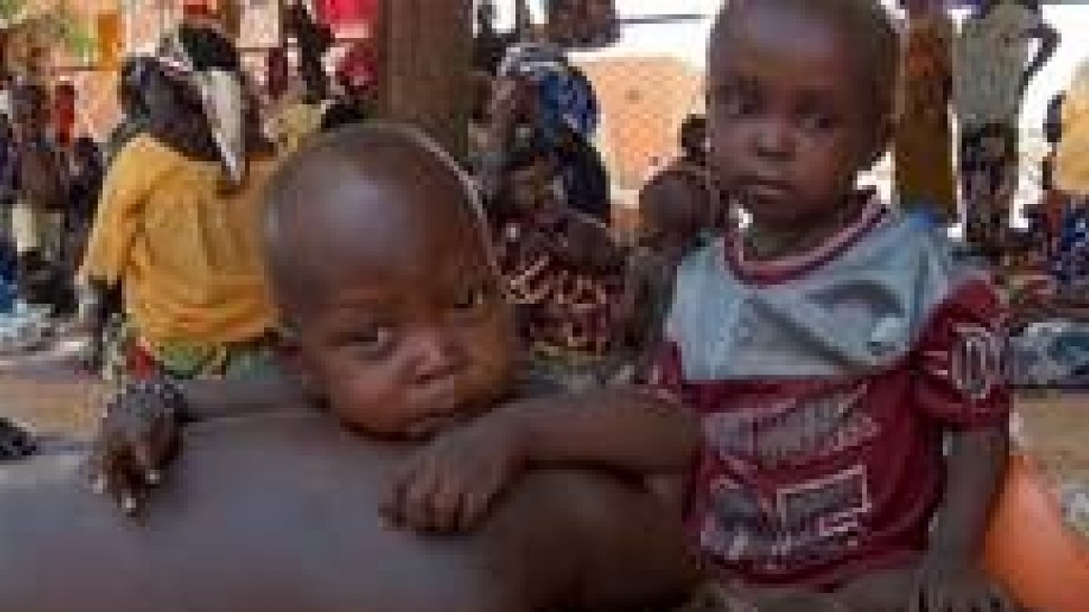 Un niño nigeriano víctima de la malnutrición, tumbado sobre su madre, espera ayuda en Maradi