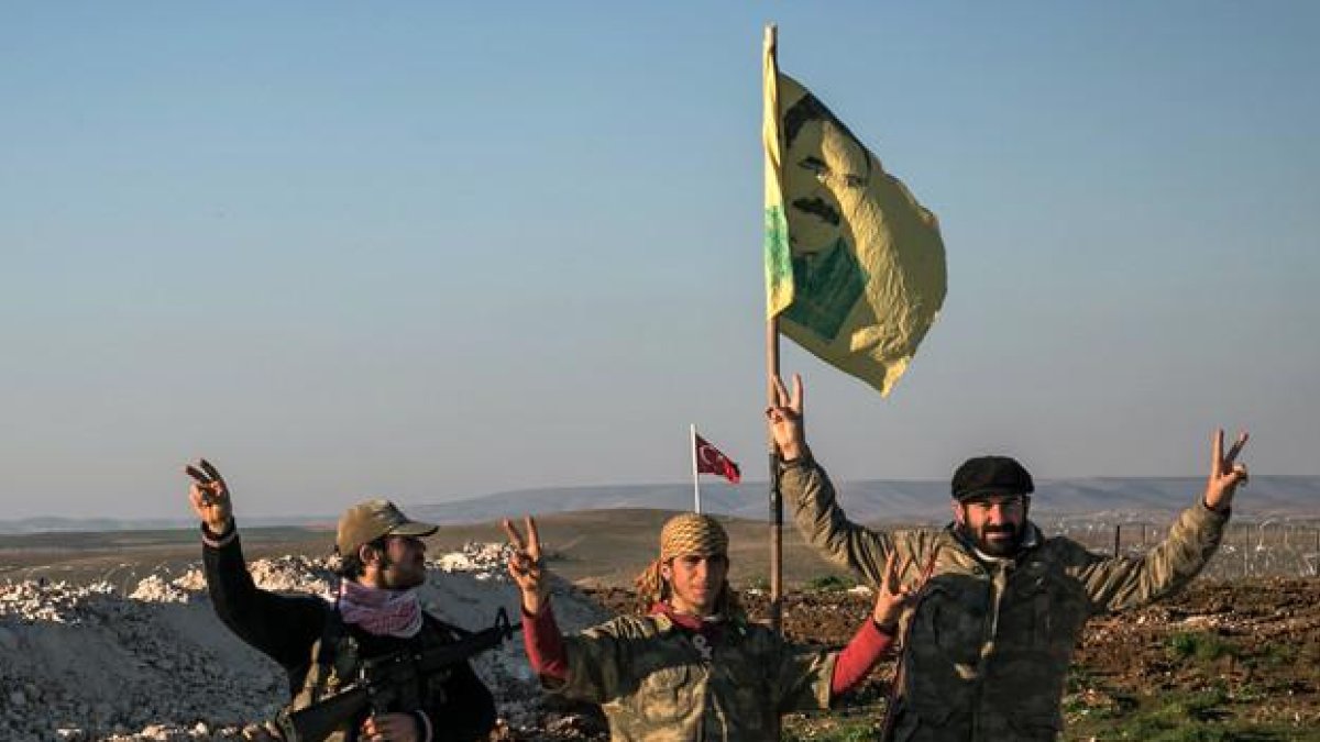 Milicianos kurdos con una bandera del líder del PKK, Abdulá Ocalán, en las cercanías de la ciudad siria de Alepo.
