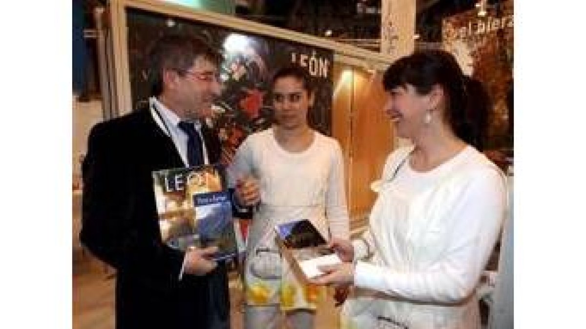 El alcalde de León, Francisco Fernández, conversa con dos azafatas del stand de León en Fitur