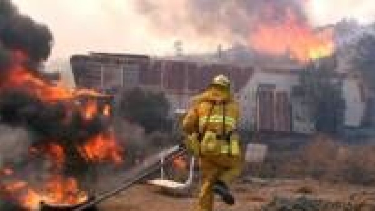 Un bombero corre para intentar sofocar las llamas que rodean una casa móvil, ayer en Los Ángeles