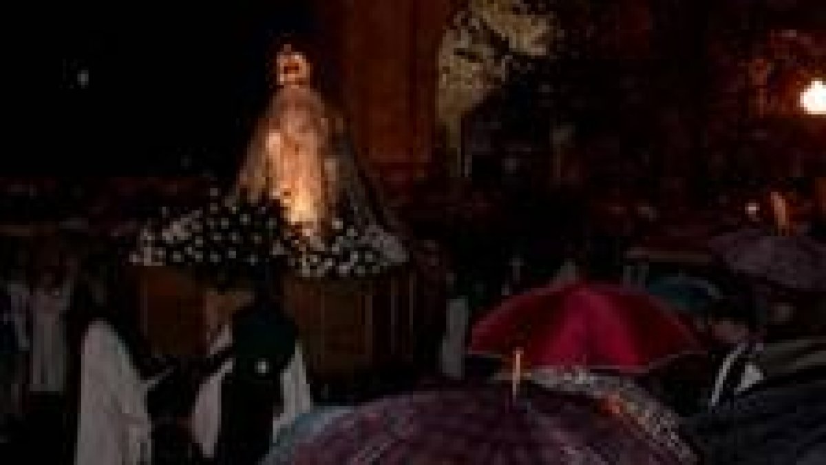 Los paraguas recibieron a una Virgen de la Esperanza cubierta por un plástico