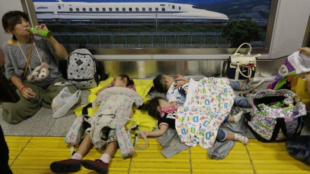 Tres niñas duermen en una estación por la cancelación de vuelos domésticos debido a la llegada del tifón Man-yi.