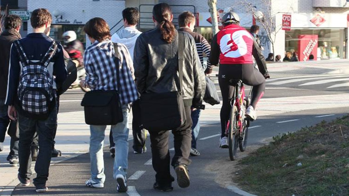 Un grupo de estudiantes, junto a un ciclista, transitando por un carril-bici cerca de la Universidad.