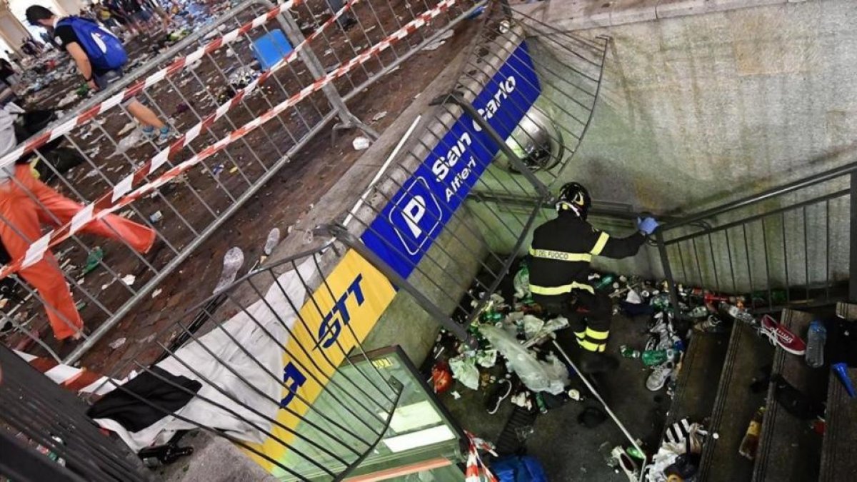 Un bombero inspecciona una valla que cedió en la plaza de San Carlos de Turín, probable origen de la estampida.