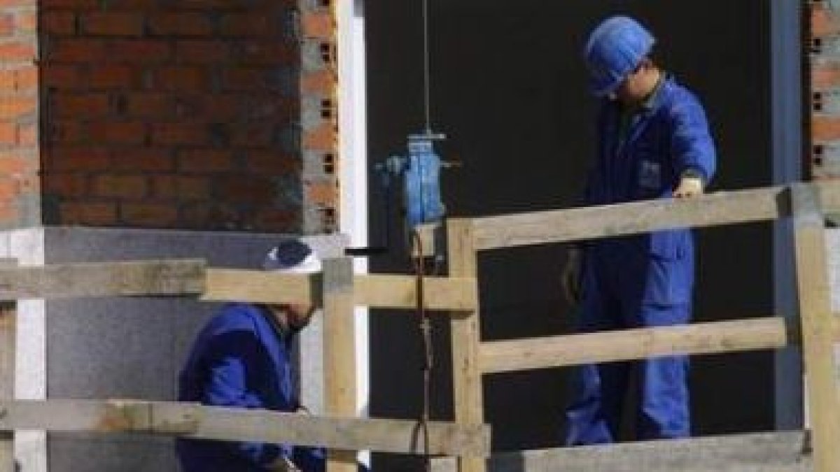 Dos trabajadores colocán elementos de seguridad en un edificio en construcción.