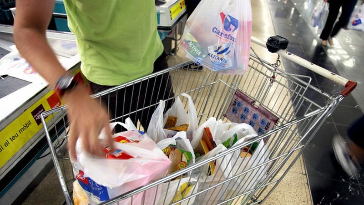 Un cliente llena el carrito de la compra en una gran superficie.