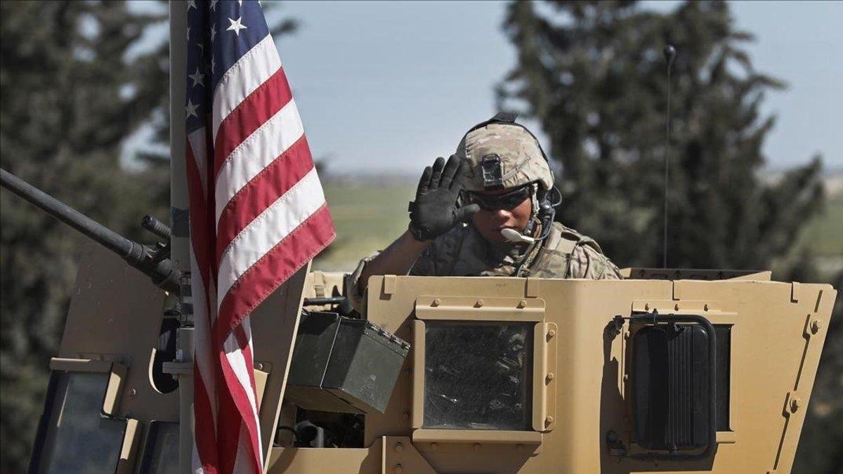 Un soldado de EEUU saluda desde un vehículo blindado en una carretera que conduce a la ciudad de Manbij, al norte de Siria.