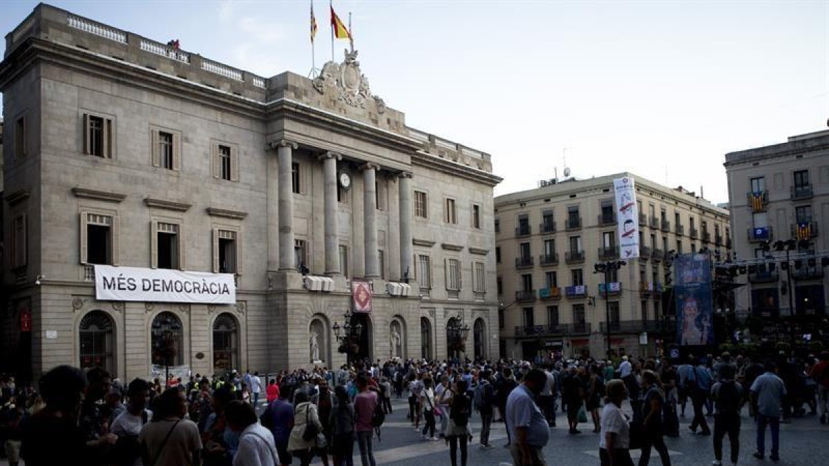 Una pancarta el lema "Més Democràcia" , cuelga de la fachada del Ayuntamiento de Barcelona.