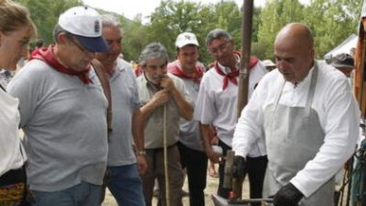 Varios romeros observan el trabajo de un herrero en la explanada del santuario.