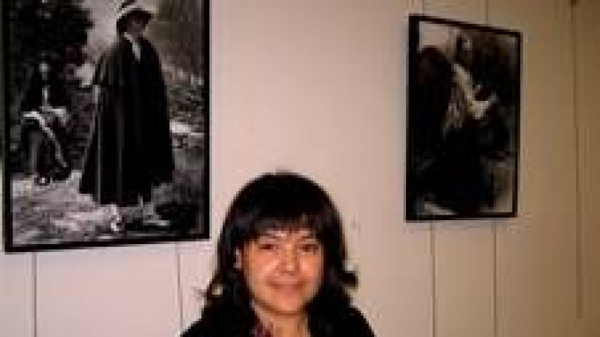 La fotógrafa castellana Esther Adrián, junto a dos de sus fotografías expuestas en el Club de Prensa