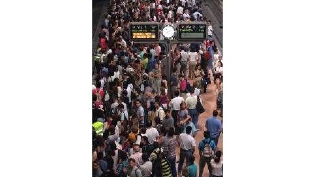 Un gran número de viajeros esperan en los andenes de Atocha