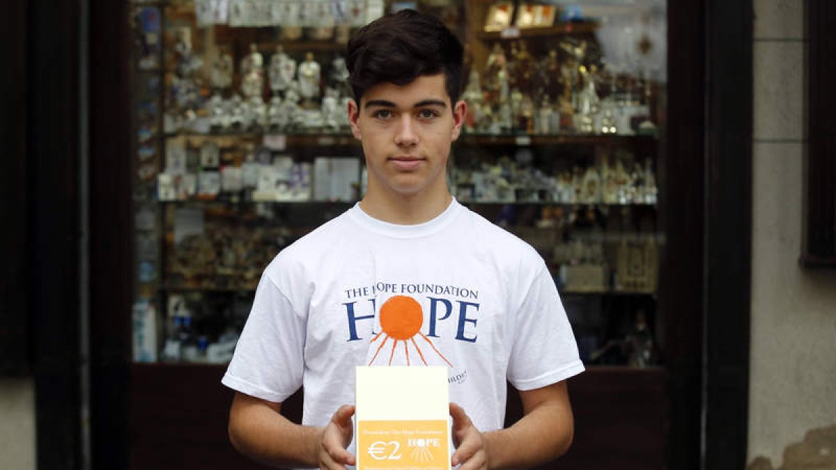 El joven cooperante Lucas Sevillano muestra una caja de las chocolatinas que vende para la infancia en India.