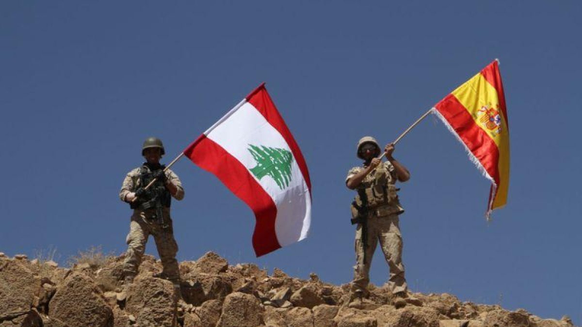 Dos soldados ondean las banderas libanesa y española tras recuperar parte de la región de Ras Baalbek.