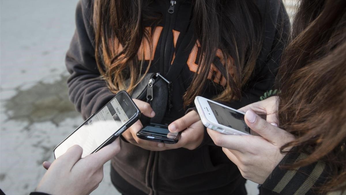 Unas adolescentes usan sus teléfonos móviles.