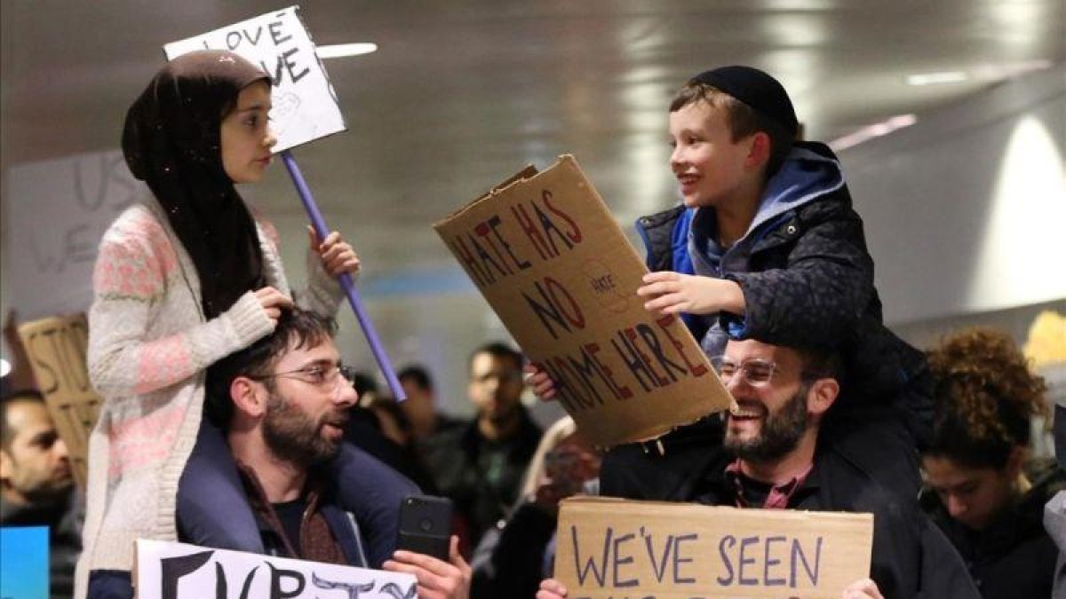 Adin y Meryem sentados sobre los hombros de sus padres, Jordan Bendant-Appell, un rabino, y Faith Yildrim, un musulmán, en una manifestación en Chicago.