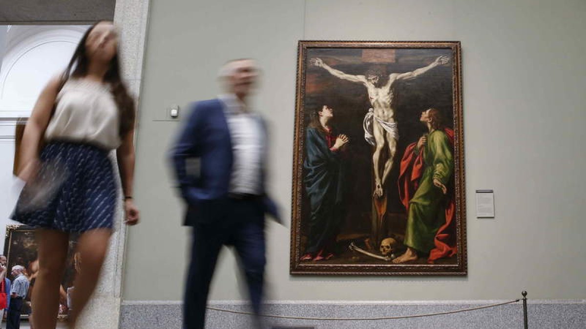 Don visitantes pasan ante el ‘Calvario’, de Luis Tristán, en una de las salas del Museo del Prado, en Madrid.