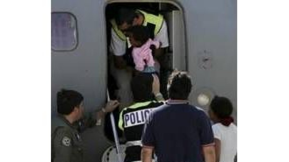 Un policía español ayuda a subir al avión a la única niña del grupo