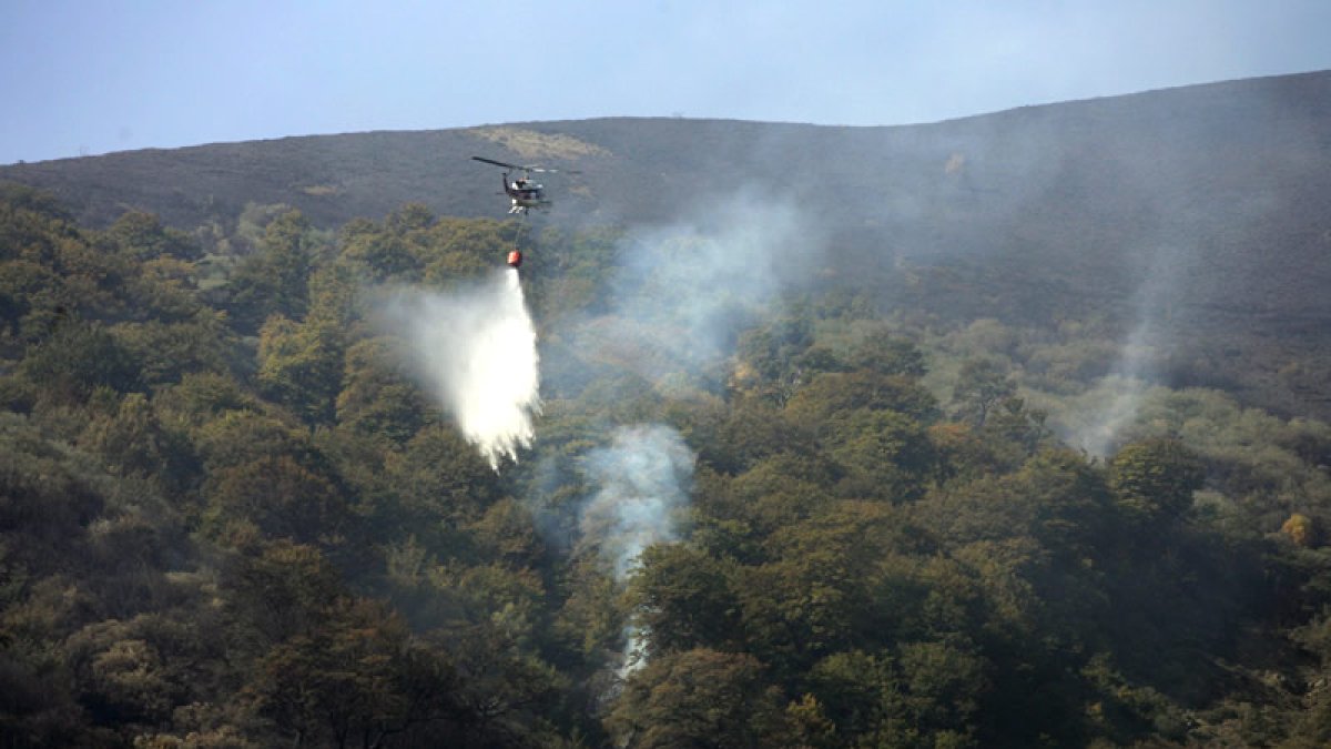 Uno de los helicópteros de extinción, actuando sobre el fuego, en Cármenes.