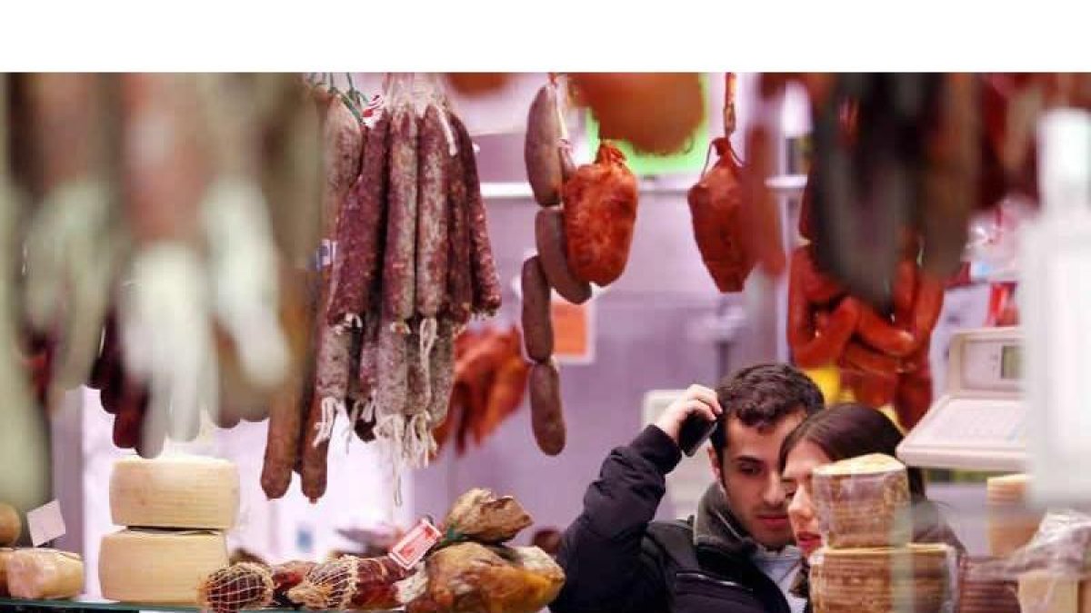 Una pareja realiza sus compras en un puesto del mercado del Conde donde se venden productos cárnicos leoneses.