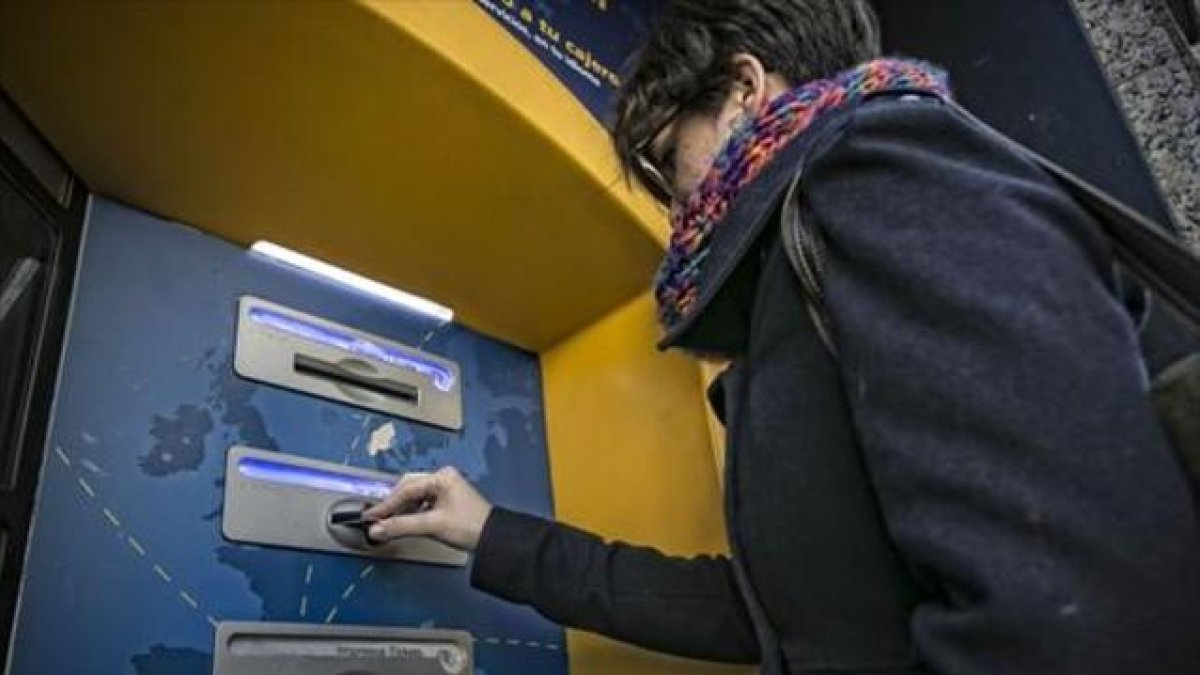 Una clienta bancaria utiliza su tarjeta en un cajero automático