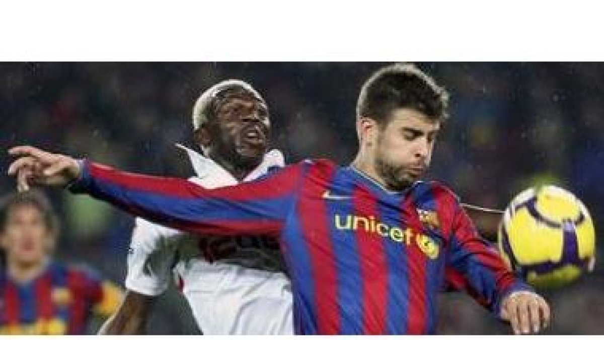 Piqué trata de proteger el balón ante el jugador del Sevilla Arouna Koné en un pulso en el que el Ba