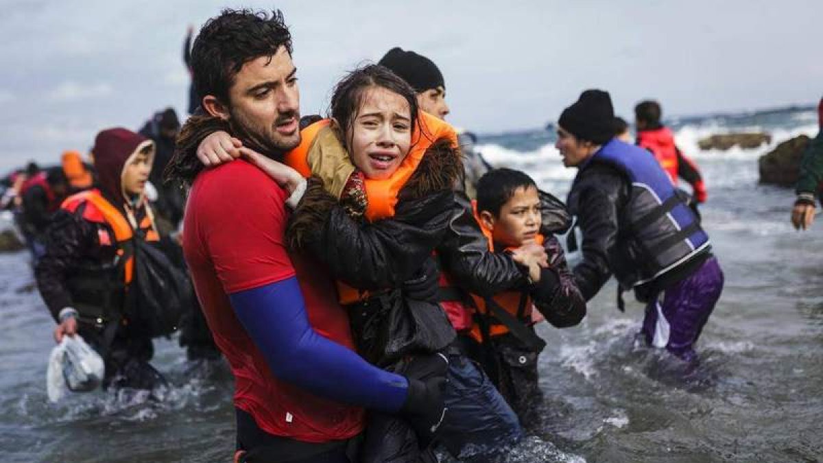 Uno de los bomberos rescata a una niña empapada y con síntomas de hipotermia en Lesbos. acnur