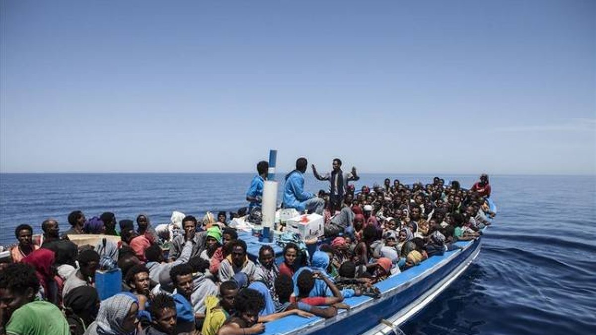 Inmigrantes a bordo de una patera intentando cruzar el Mediterráneo son rescatados por la Marina Militar italiana.
