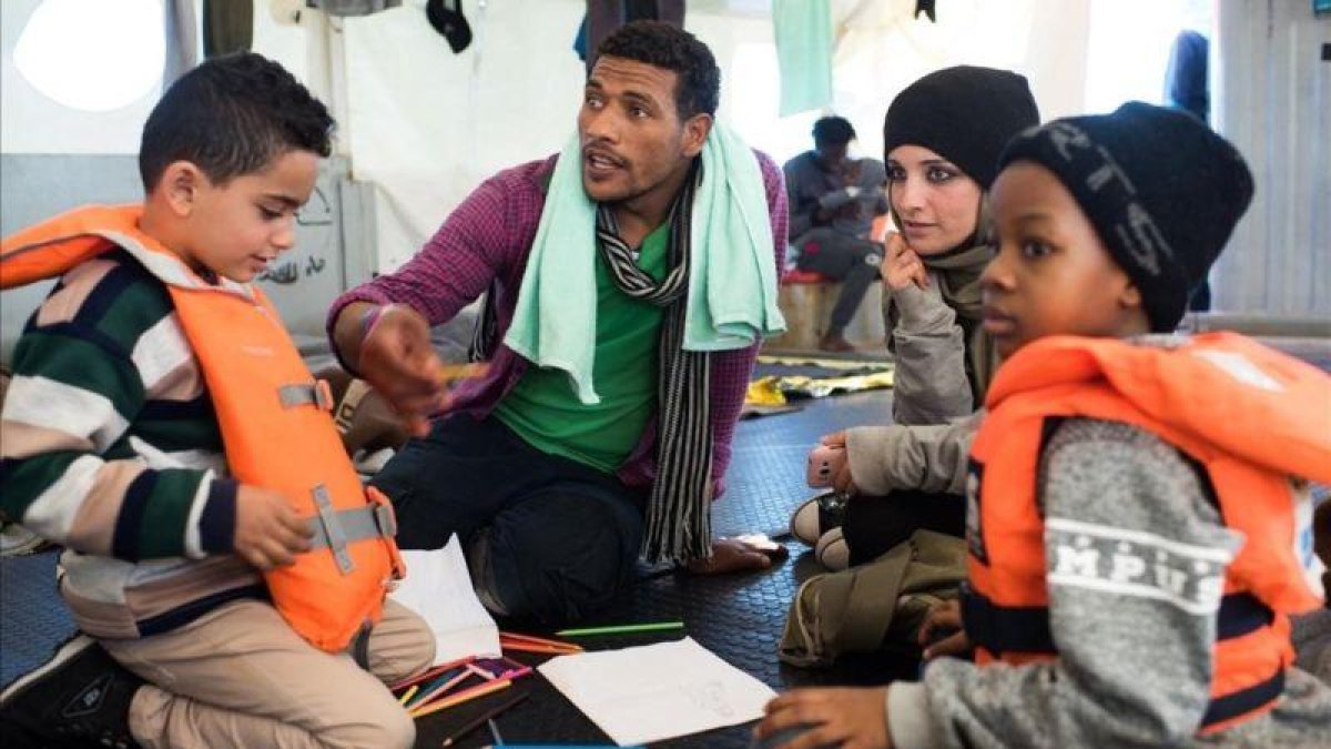 Fotografia cedida por la ONG Sea-Watch que muestra a Nasreen  2d  y a su hijo Zizou  i  junto a otros inmigrantes a bordo del buque Sea Watch 3 en el mediterraneo el 23 de diciembre de 2018.