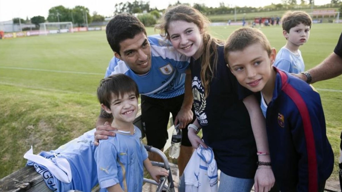 Luis Suárez posa con una jóvenes aficionados tras su primer entrenamiento con la selección uruguaya.