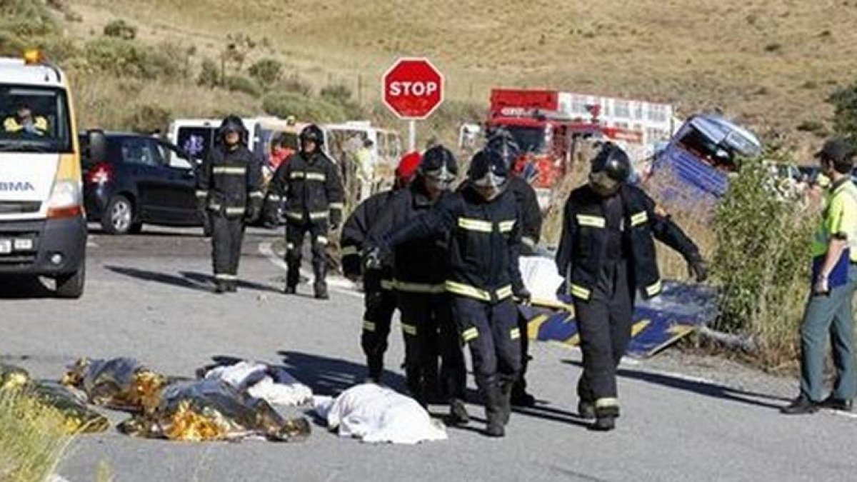 Miembros de los servicios de emergencia transportan en camilla a una víctima del accidente y pasan junto a algunos cadáveres, este lunes.