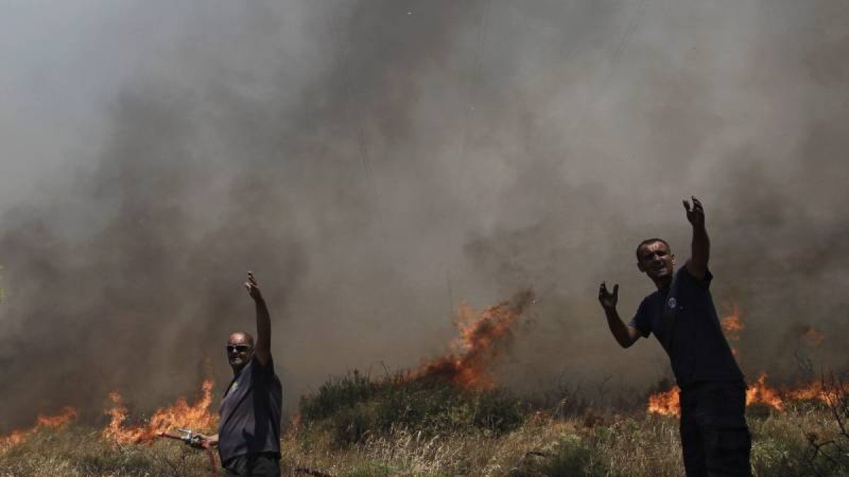 Bomberos tratan de sofocar un incendio en el suburbio de Ilioupoli en Atenas (Grecia).