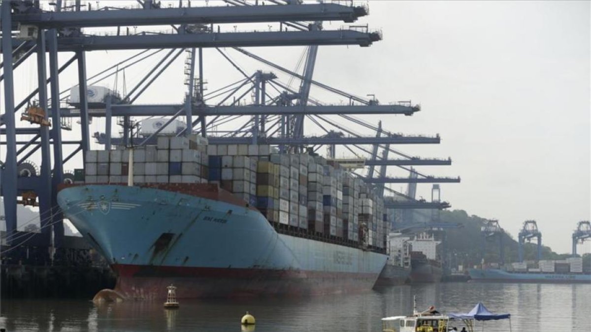 Un barco carga contenedores al lado del nuevo Canal de Panamá.