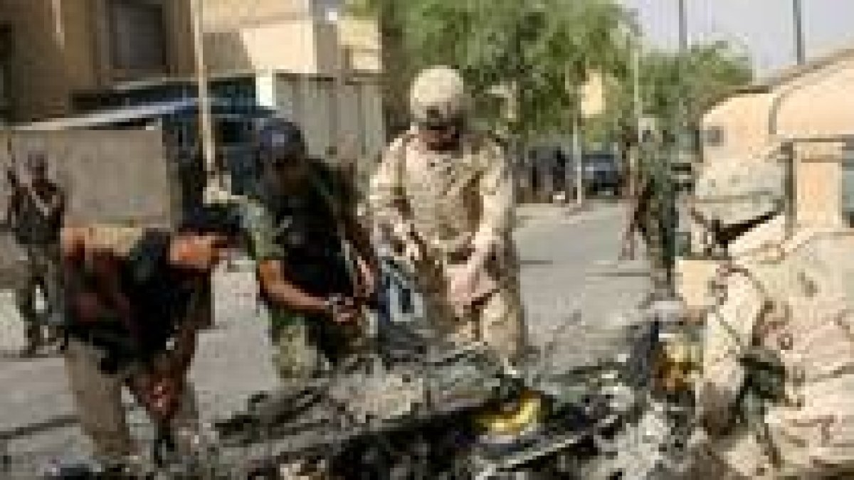 Soldados estadounidenses contemplan el lugar donde hizo explosión un coche bomba en Bagdad