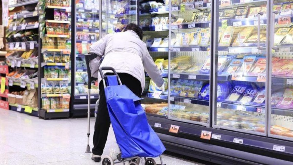 Una mujer en la sección de productos congelados de un supermercado.