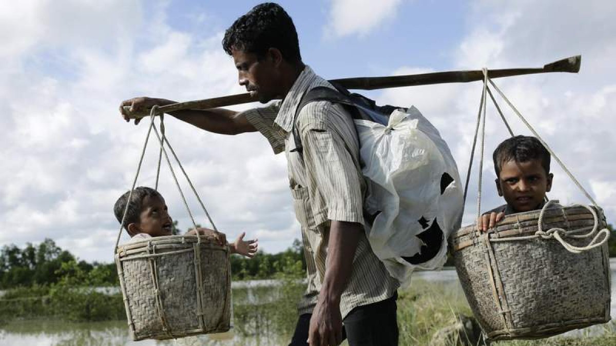 Un padre carga con sus dos hijos para cruzar la frontera entre Birmania y Bangladesh a través del río Naf. ABIR ABDULLAH